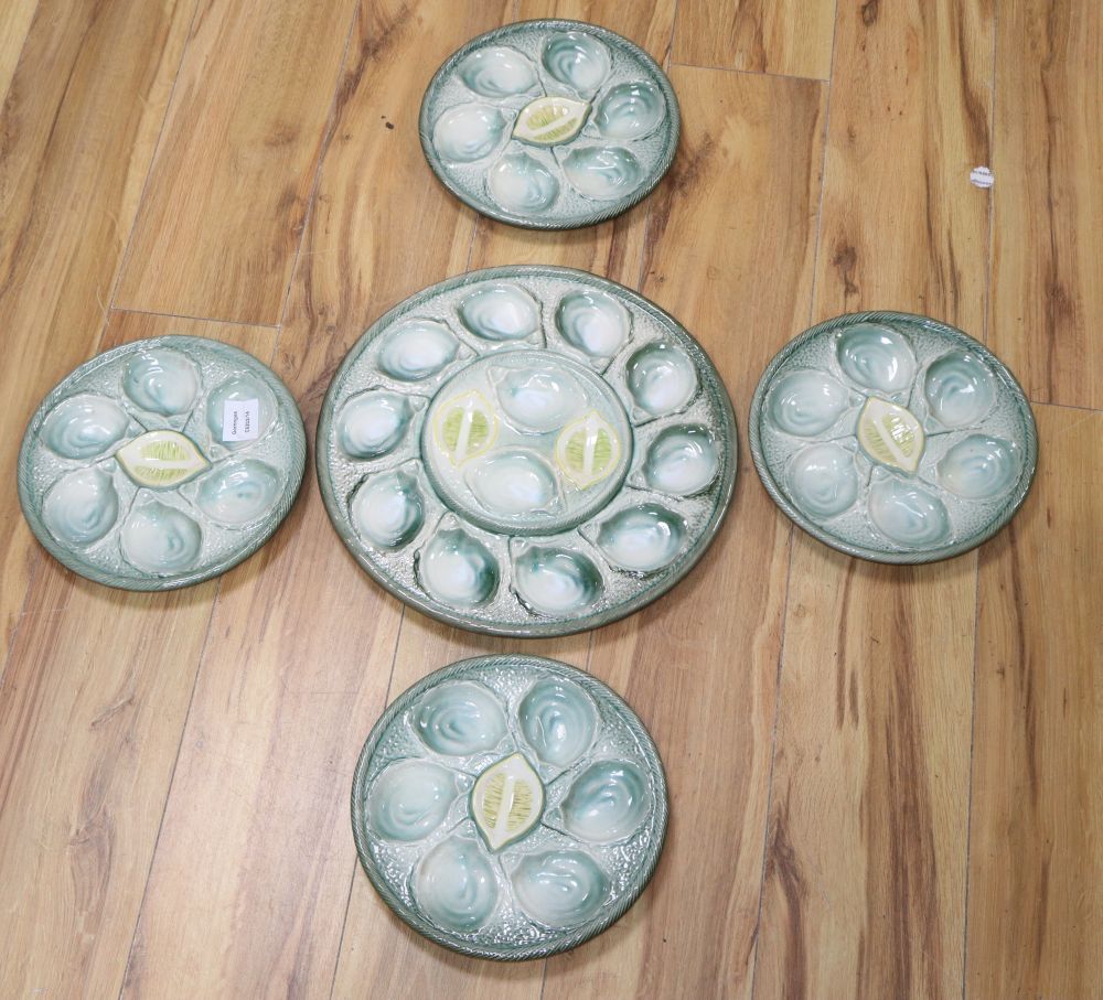 A set of four pottery oyster dishes, and a platter, the platter diameter 37cm